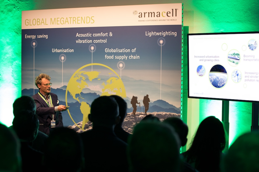 Redner bei den Armacell Armarium Days mit grafischen Event-Aufstellern Redner vor Publikum bei der Armacell Führungskräftetagung Armarium Days mit großformatigen Grafik-Aufstellern und Präsentationsfläche.