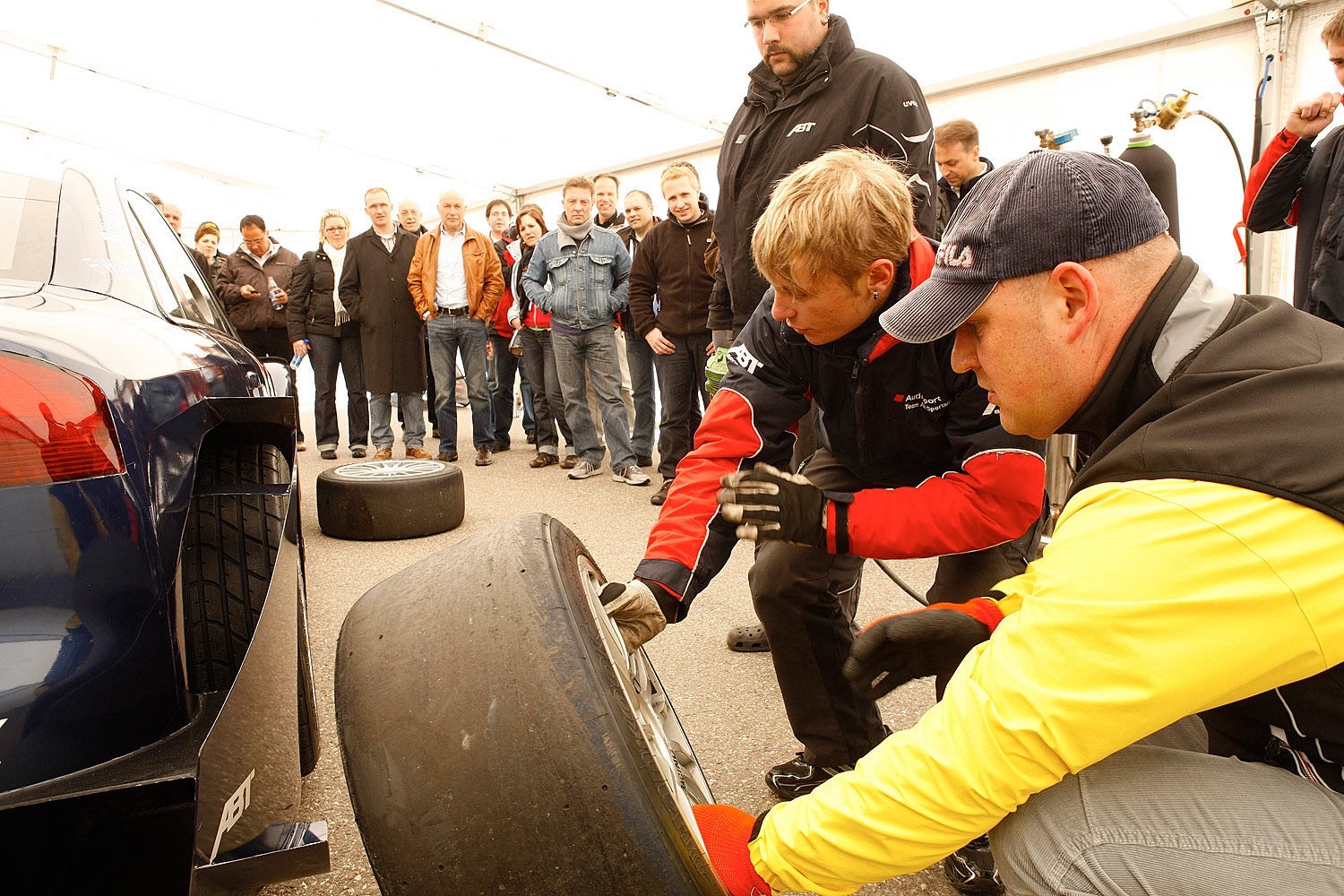 Team-Building Challenge beim EMC Power und Speed Event Teilnehmer wechseln Reifen bei einer Team-Building Challenge des EMC Partner-Events