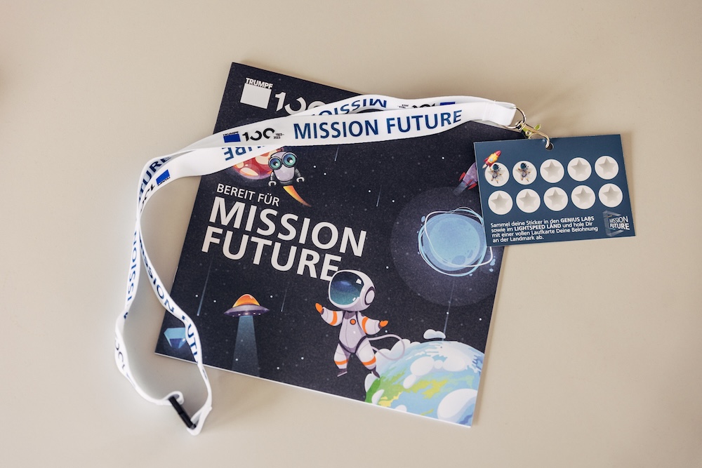 Branded event materials for TRUMPF 100 Mission Future Keyrings, notebooks, stickers and cards featuring the Mission Future branding for the TRUMPF 100 Family Festival